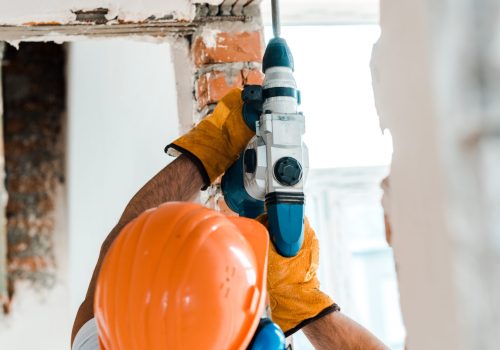 back view of handyman using hammer drill on wall